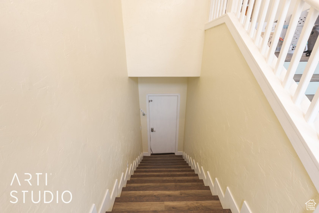 Staircase with wood finished floors and a textured wall