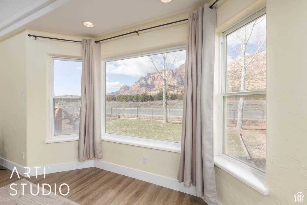 Unfurnished dining area featuring wood finished floors, plenty of natural light, a mountain view, and recessed lighting