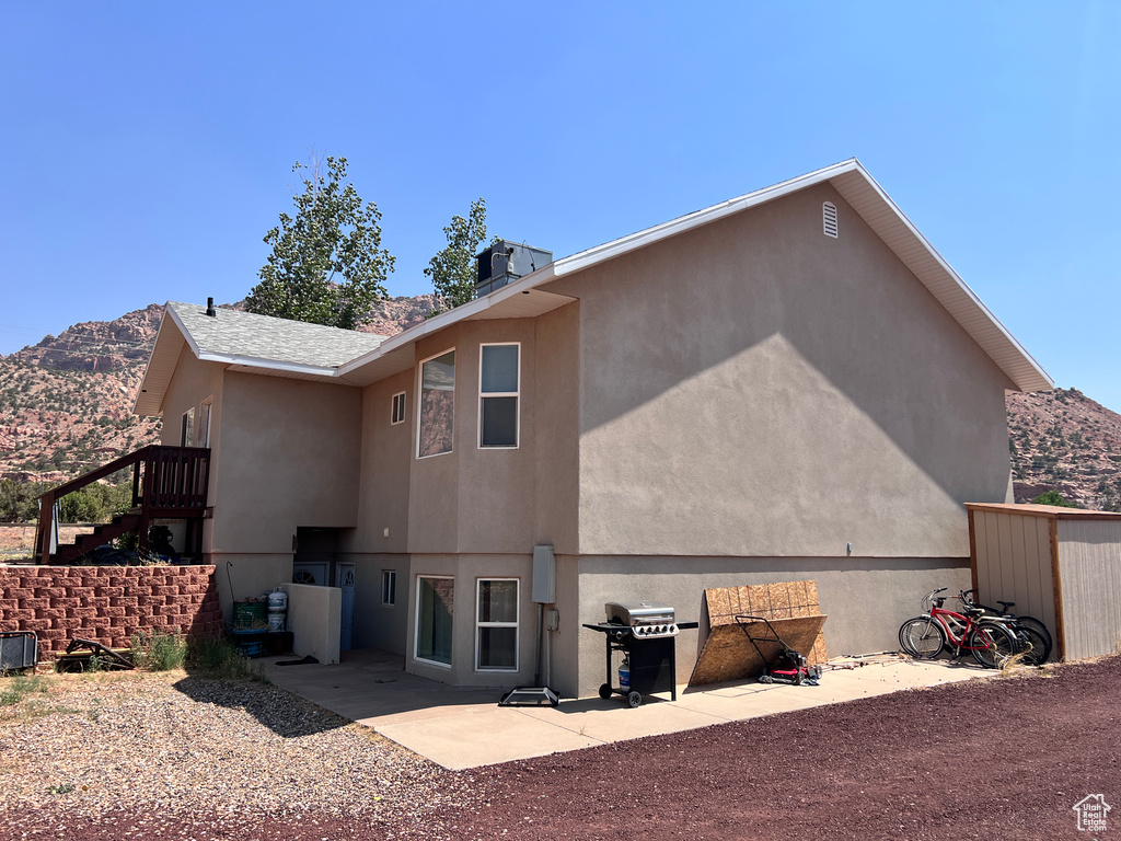 Rear view of property featuring a mountain view, stucco siding, stairway, and a patio area