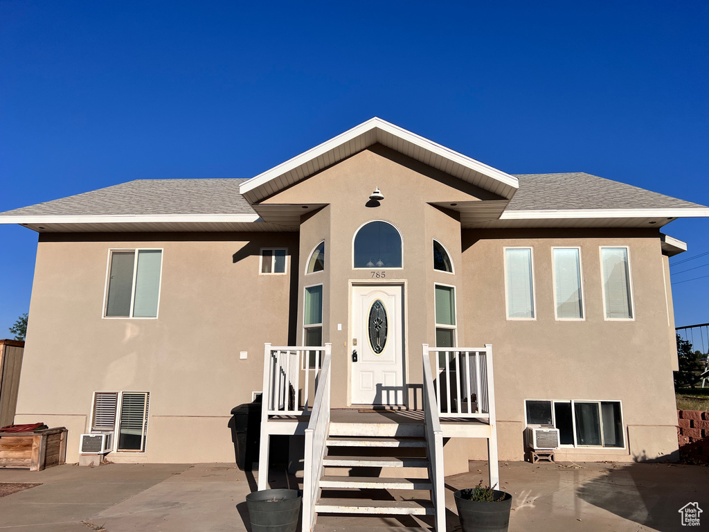 View of front of house with stucco siding, roof with shingles, and a patio