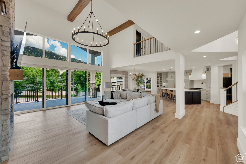Living room featuring a chandelier, a high ceiling, beam ceiling, light wood finished floors, and recessed lighting