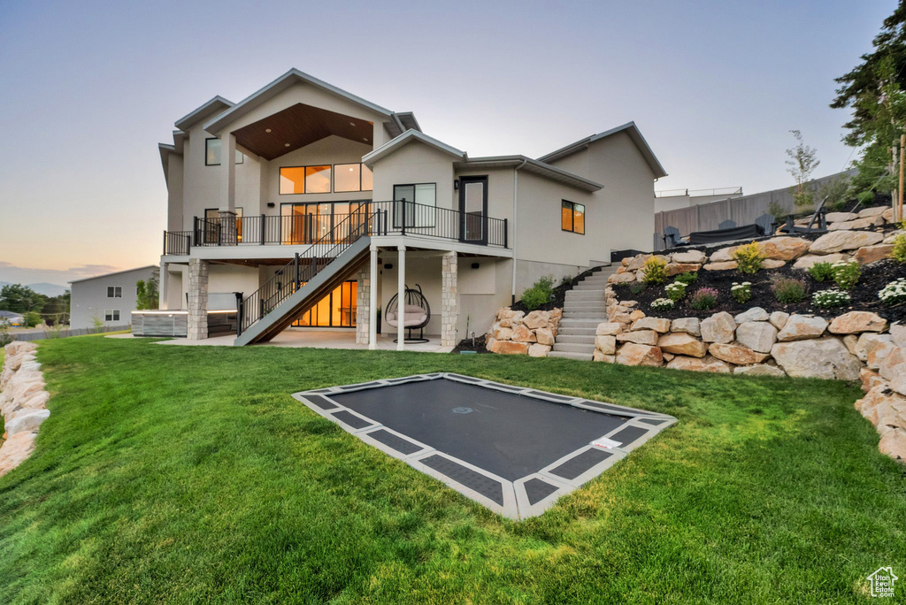 Back of house with stairs, a trampoline, stucco siding, a wooden deck, and a patio area
