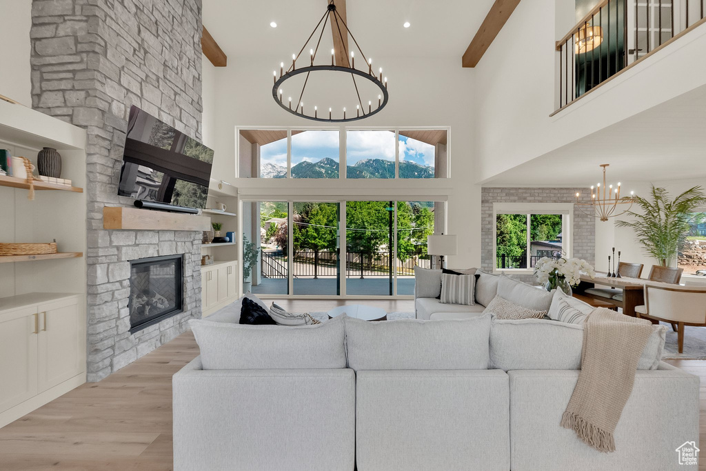 Living room with a chandelier, a high ceiling, a fireplace, wood finished floors, and plenty of natural light