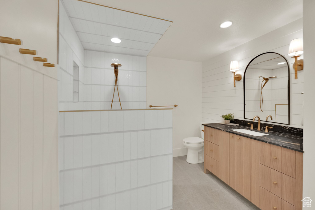 Full bath featuring tiled shower, vanity, recessed lighting, and wooden walls