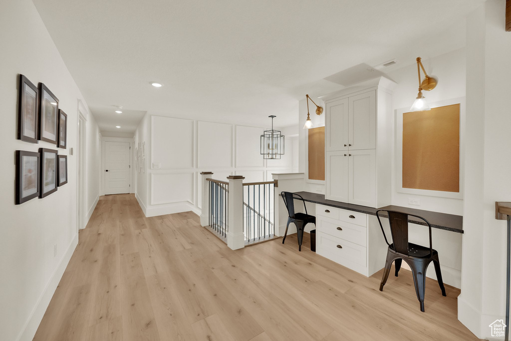 Hallway with light wood-type flooring, an office area, an upstairs landing, recessed lighting, and a decorative wall