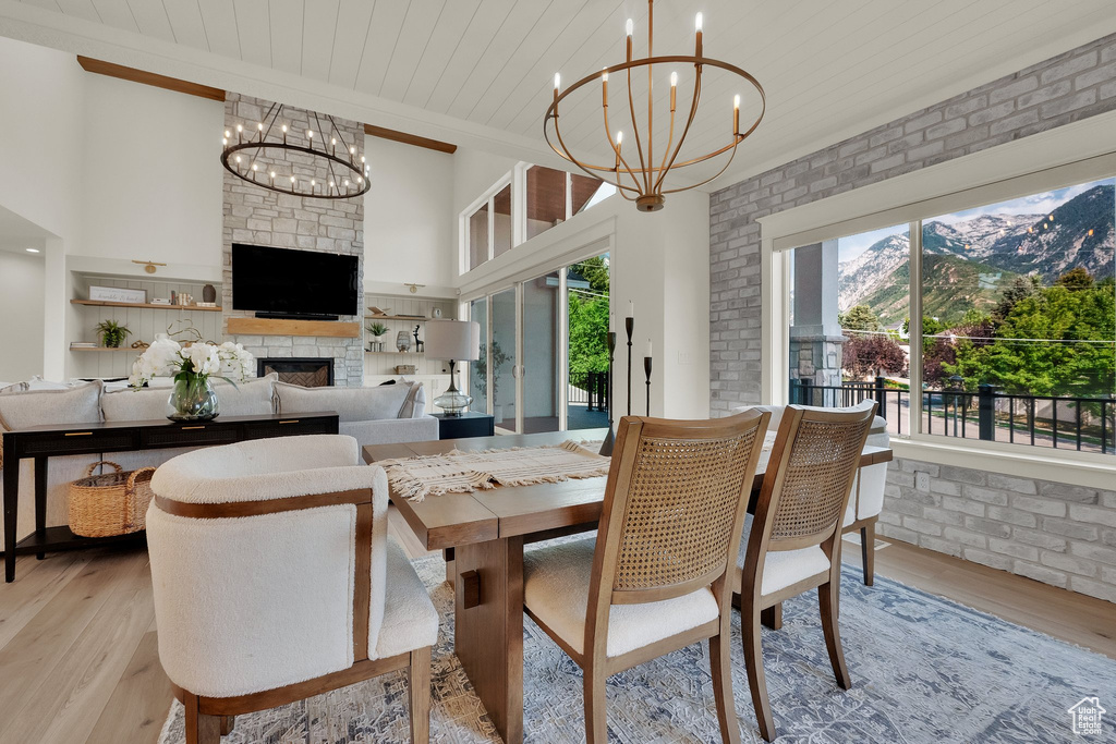 Dining space featuring a chandelier, healthy amount of natural light, light wood-style flooring, wood ceiling, and brick wall