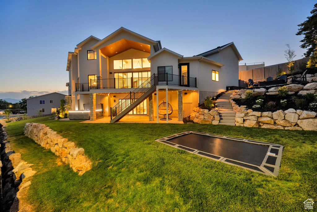 Back of house featuring stairs, stucco siding, and a yard