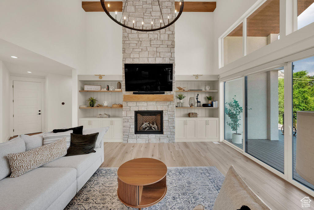 Living area with a fireplace, a high ceiling, light wood-type flooring, a chandelier, and built in features