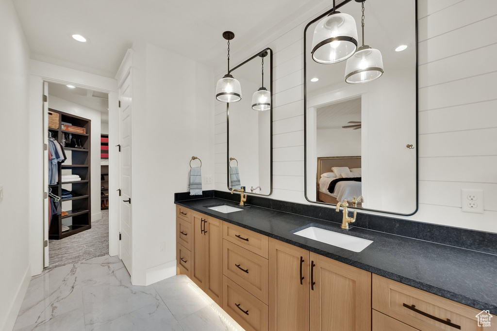 Ensuite bathroom featuring marble look tiles, double vanity, a spacious closet, and recessed lighting