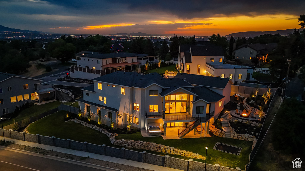 Back of property at dusk featuring a fenced backyard, an outdoor fire pit, a balcony, stairway, and a mountain view