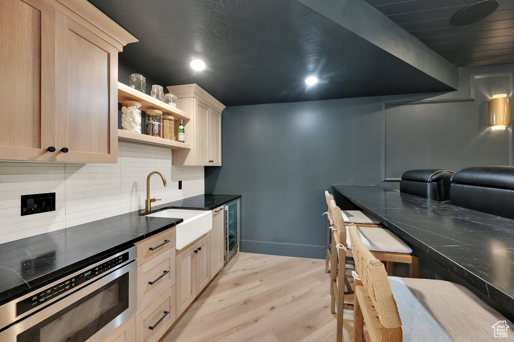 Kitchen with light wood-style floors, backsplash, open shelves, dark stone countertops, and recessed lighting