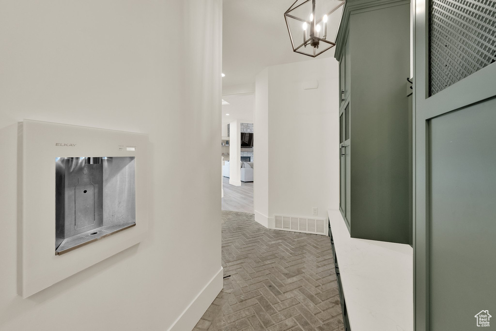 Corridor featuring brick patterned floors and a chandelier