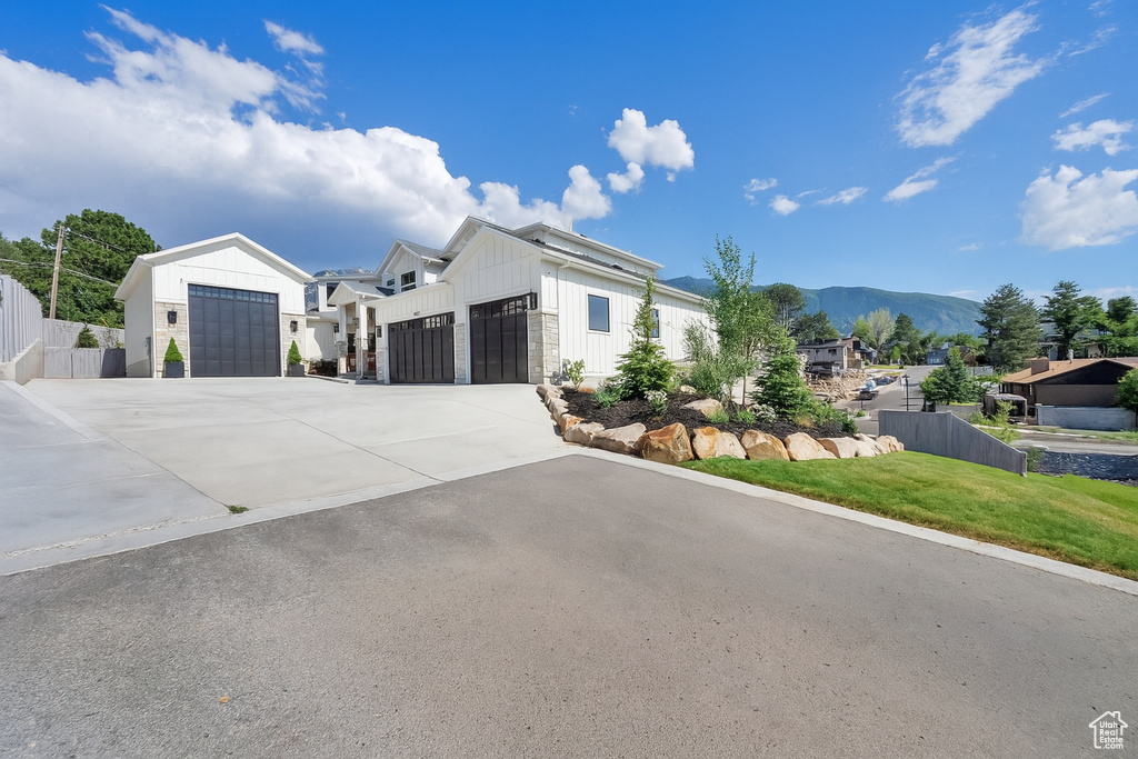 View of front of property featuring an attached garage, board and batten siding, concrete driveway, and a mountain view