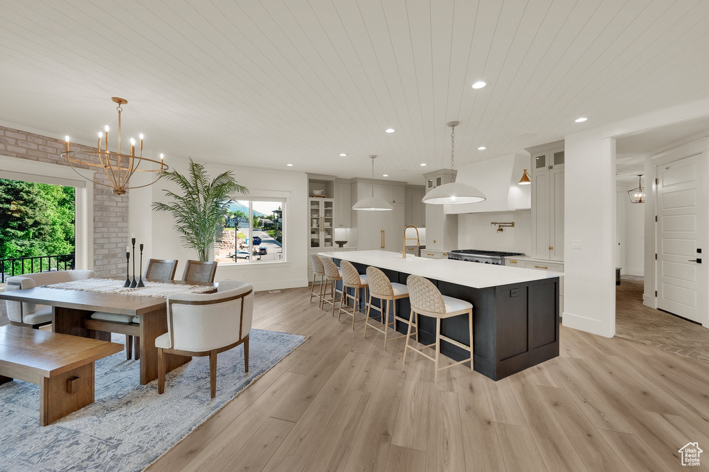 Dining space featuring healthy amount of natural light, light wood-type flooring, a chandelier, recessed lighting, and wooden ceiling
