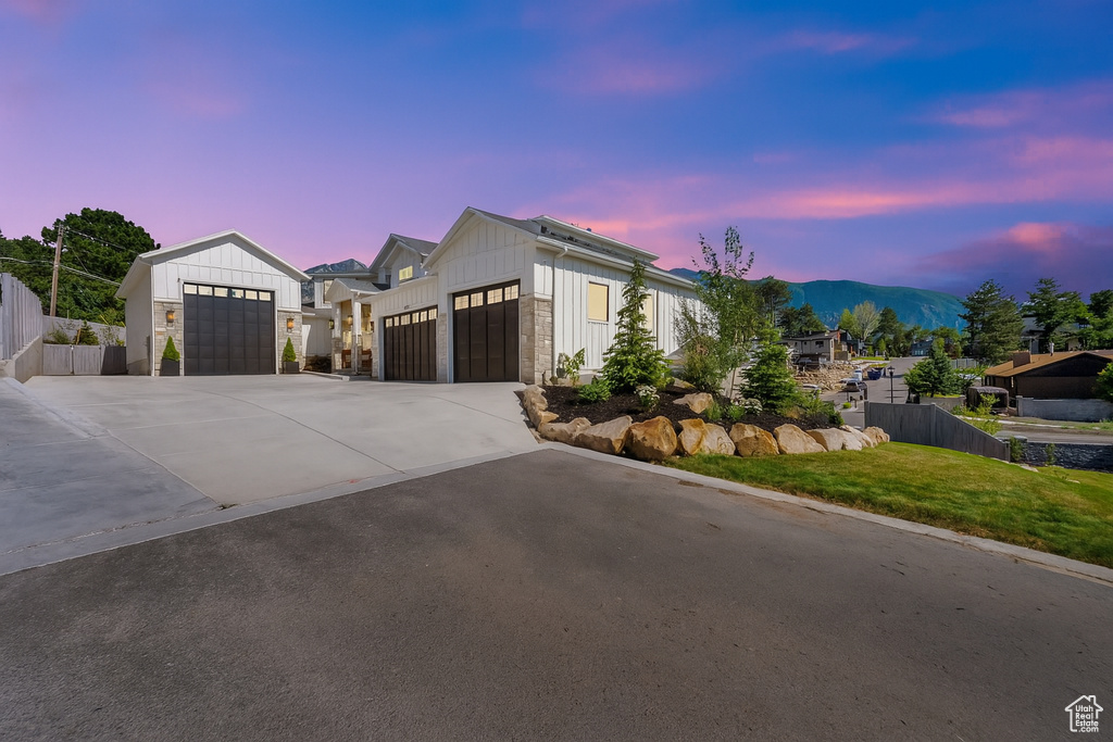 Modern farmhouse with driveway, a garage, stone siding, and board and batten siding