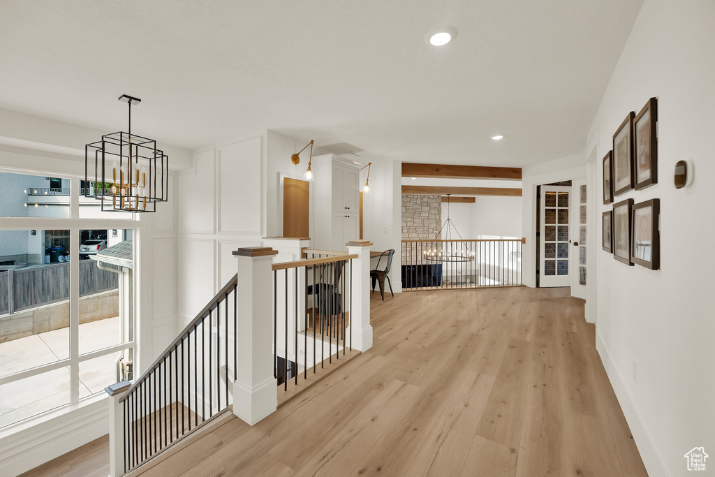 Corridor with an upstairs landing, light wood-style floors, a chandelier, and recessed lighting