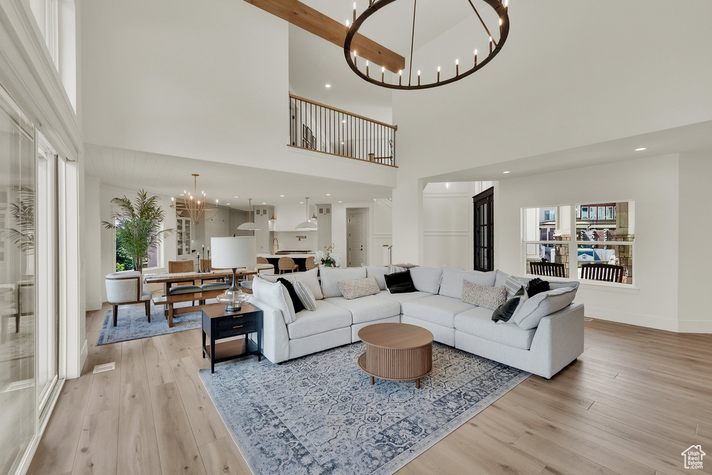 Living area featuring a chandelier, light wood finished floors, a towering ceiling, and healthy amount of natural light