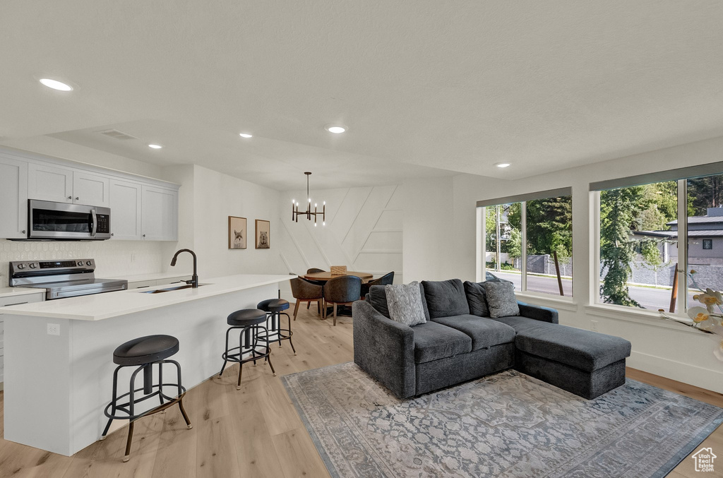 Living area with light wood finished floors, a chandelier, and recessed lighting