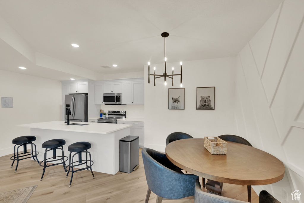 Dining area featuring light wood finished floors, a chandelier, and recessed lighting