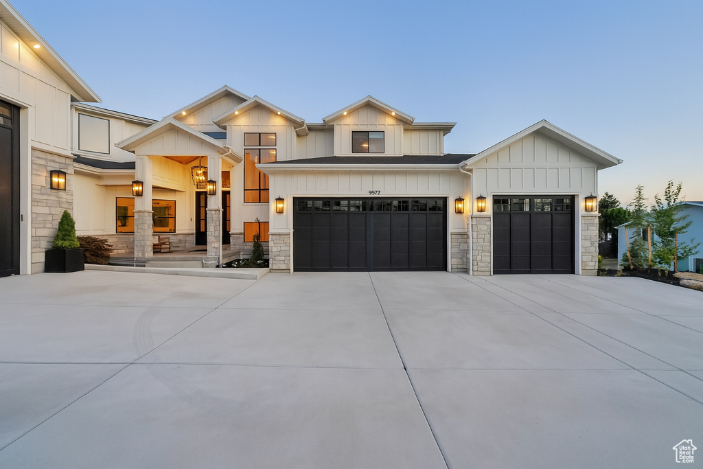 View of front of property with driveway, stone siding, board and batten siding, and an attached garage
