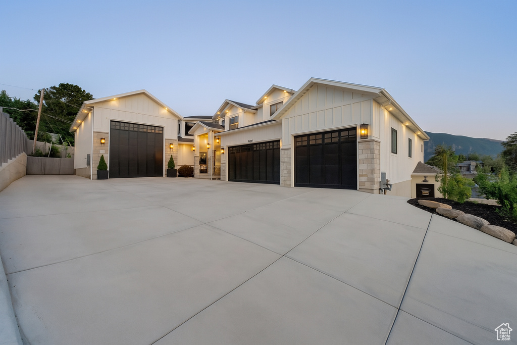 View of front facade with an attached garage, concrete driveway, board and batten siding, a mountain view, and stone siding