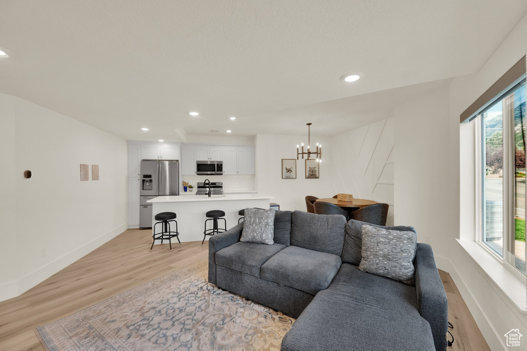 Living room with light wood-style floors, a chandelier, and recessed lighting