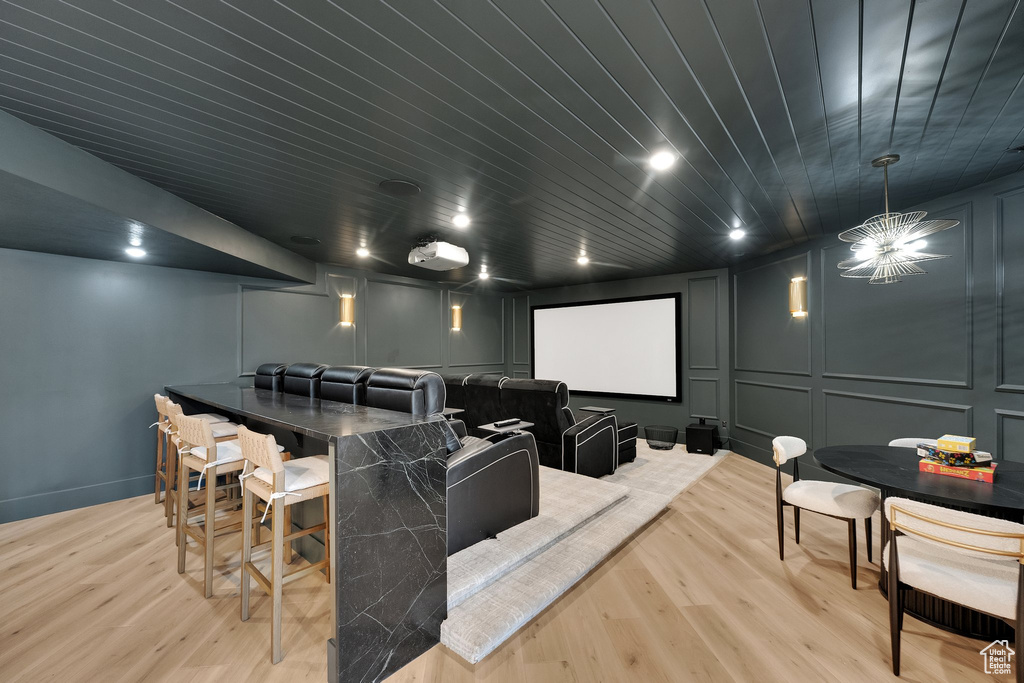 Home theater room with a decorative wall, light wood-style flooring, wooden ceiling, and recessed lighting