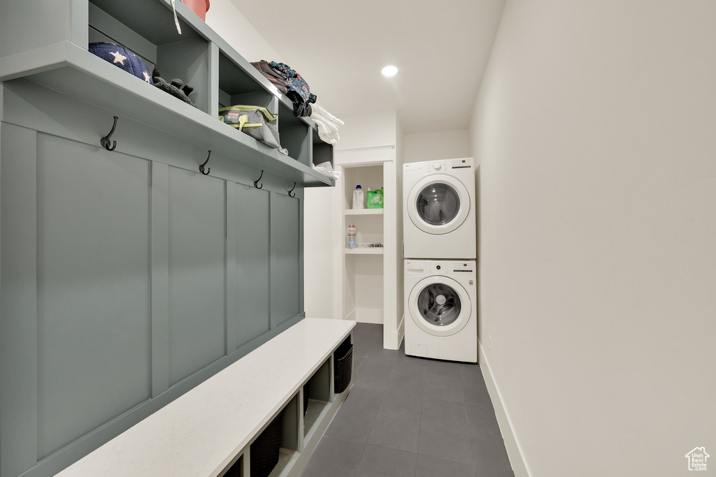 Laundry room featuring stacked washing machine and dryer and dark tile patterned flooring