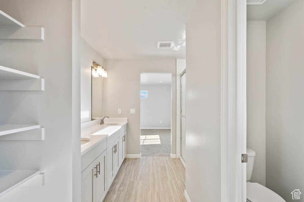 Bathroom with double vanity, a shower with shower door, and wood finished floors
