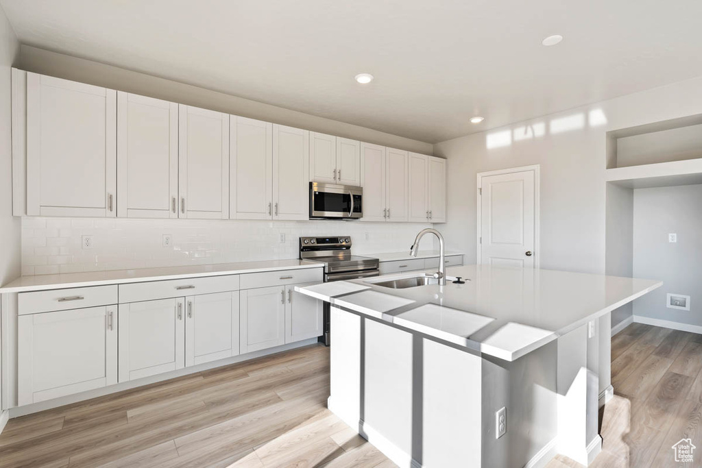 Kitchen with appliances with stainless steel finishes, light wood-style flooring, light countertops, tasteful backsplash, and recessed lighting