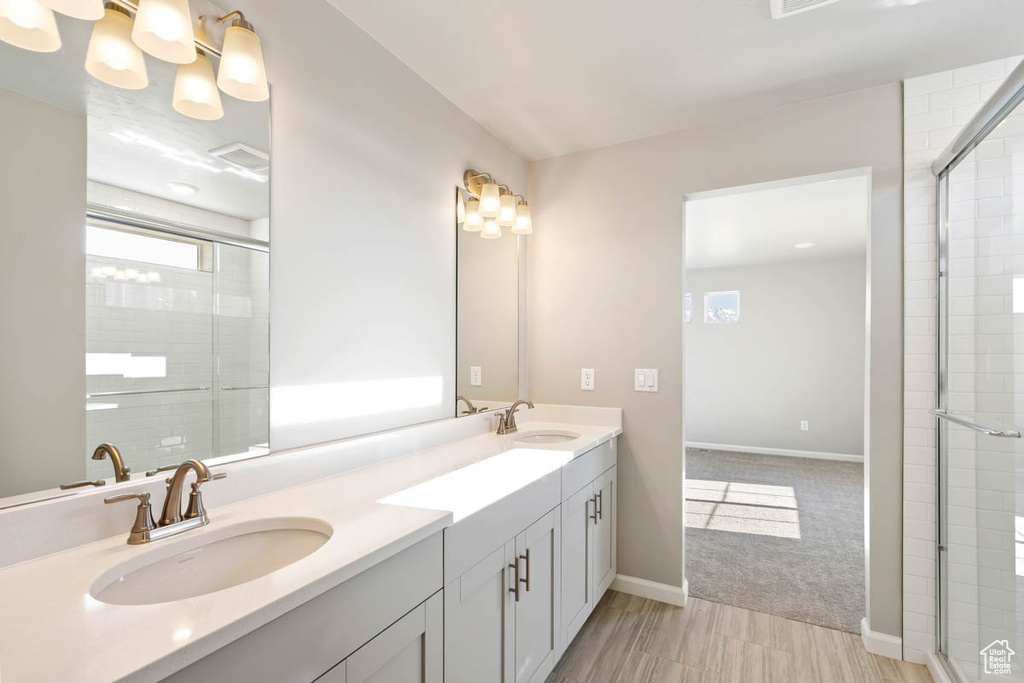 Bathroom featuring double vanity, plenty of natural light, and a tile shower