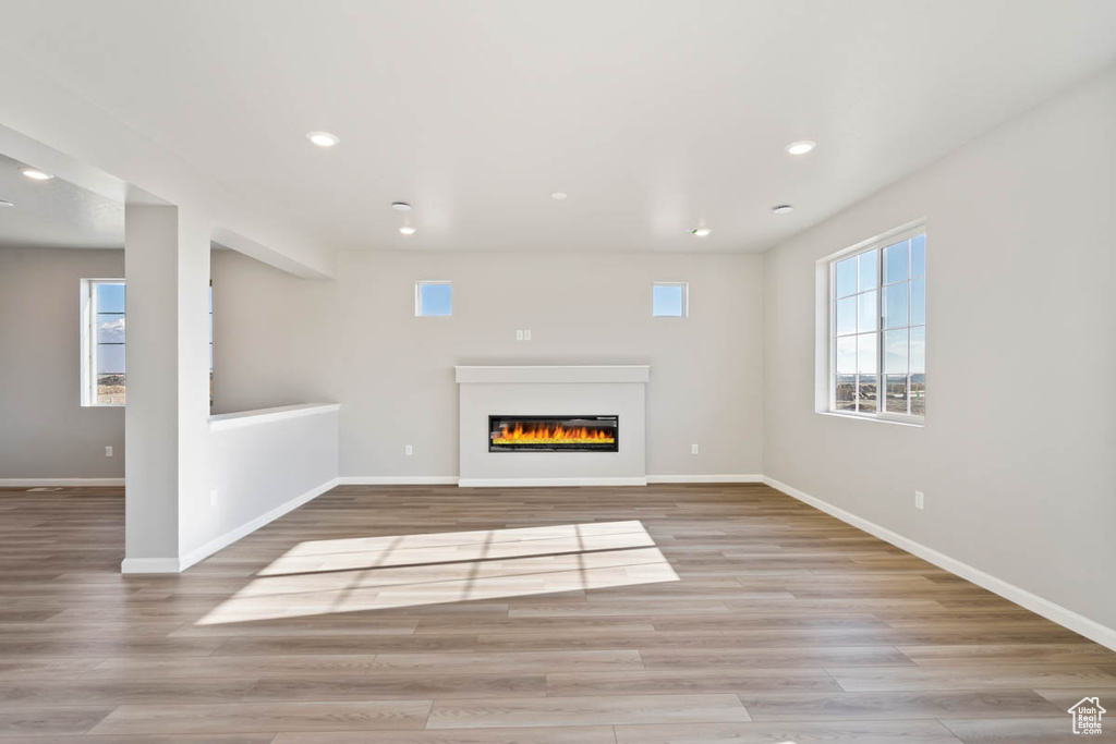 Unfurnished living room featuring wood finished floors, recessed lighting, and a glass covered fireplace