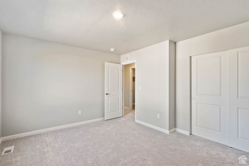 Unfurnished bedroom featuring light colored carpet and a closet