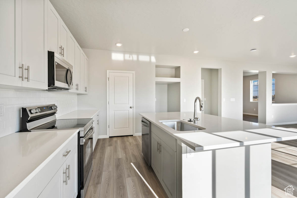 Kitchen with stainless steel appliances, tasteful backsplash, light wood-style flooring, light countertops, and recessed lighting