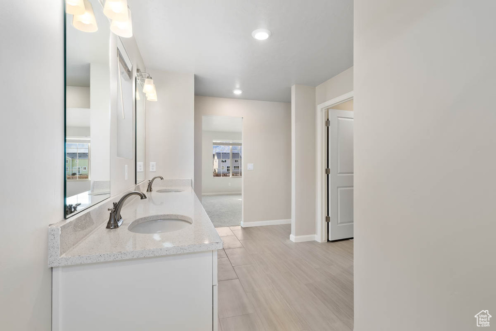 Full bath with double vanity, wood finished floors, and recessed lighting