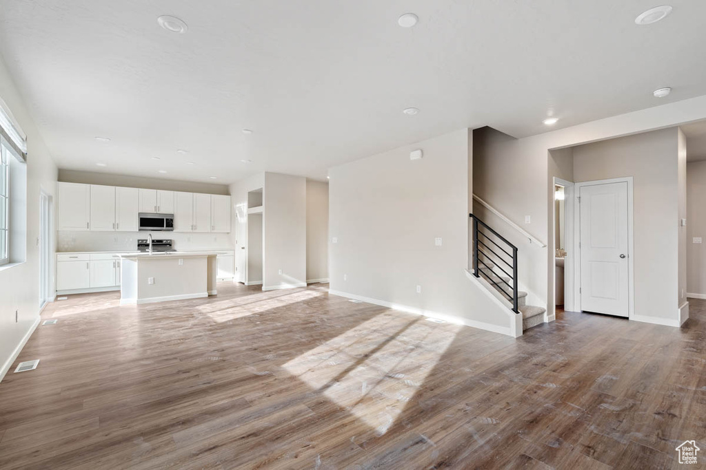 Unfurnished living room with stairs and light wood-style floors