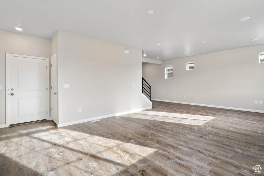 Empty room with wood finished floors, stairs, and recessed lighting