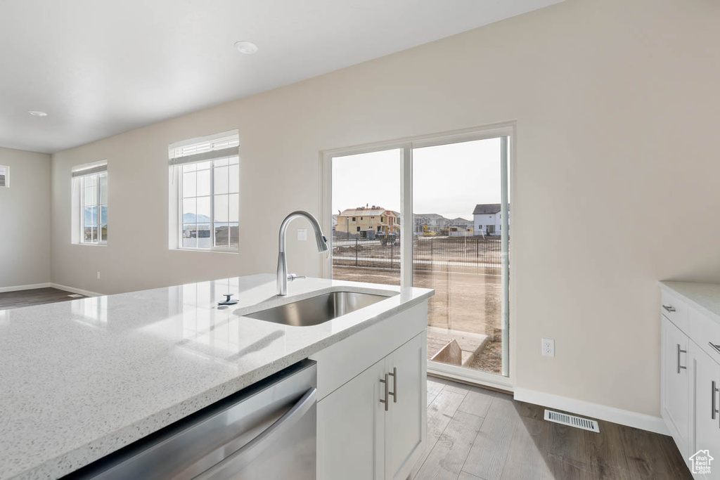 Kitchen featuring dishwasher, light stone counters, white cabinets, and light wood finished floors