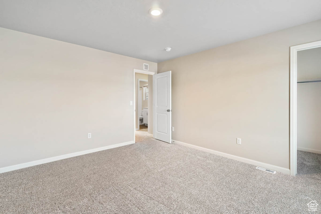 Unfurnished bedroom featuring carpet flooring, a closet, and a spacious closet
