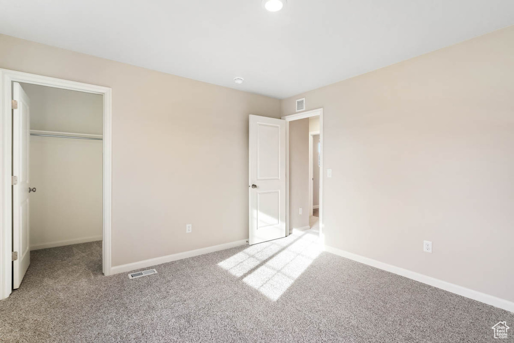 Unfurnished bedroom featuring carpet, a closet, and a walk in closet