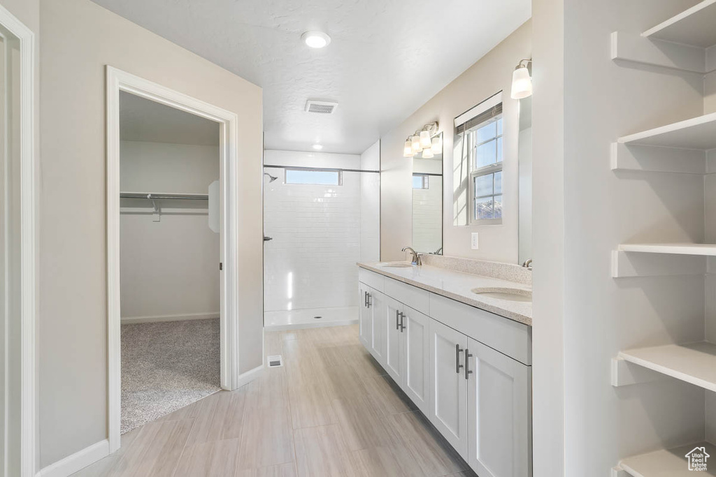 Bathroom with a stall shower, double vanity, healthy amount of natural light, and a spacious closet