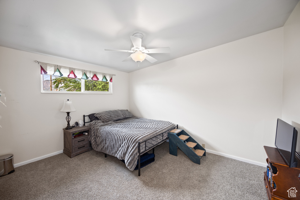 Carpeted bedroom with a ceiling fan and baseboards