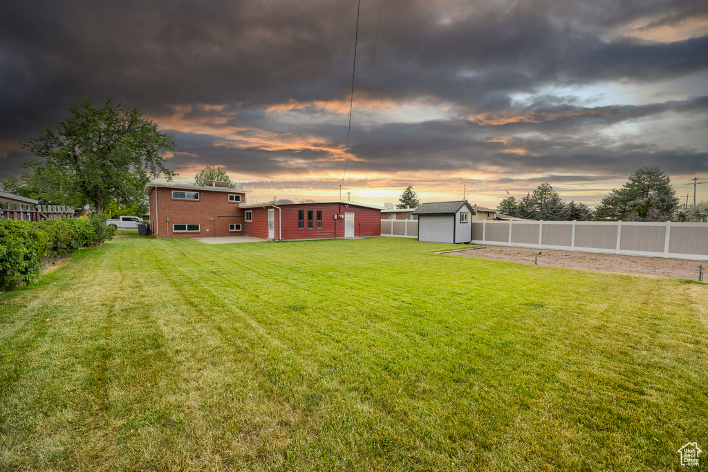 Yard at dusk featuring a fenced backyard and a shed