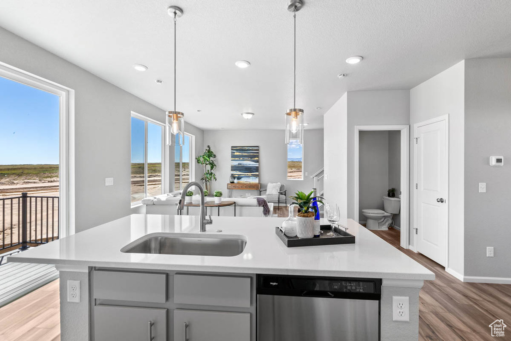 Kitchen with dishwasher, light wood finished floors, a kitchen island with sink, light countertops, and recessed lighting