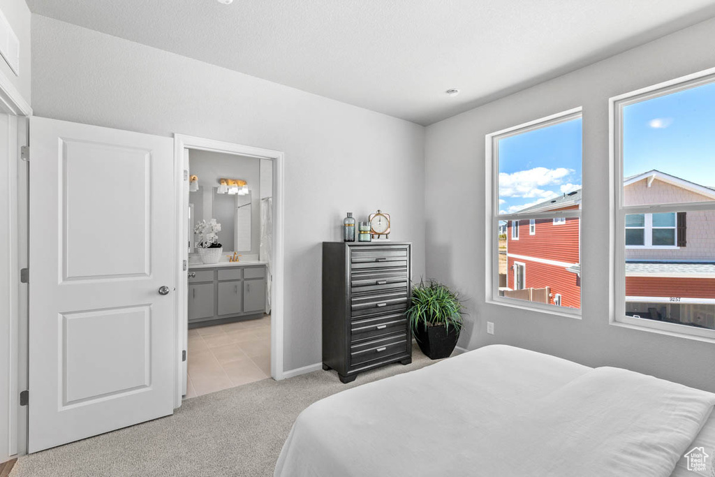 Carpeted bedroom featuring ensuite bath and baseboards