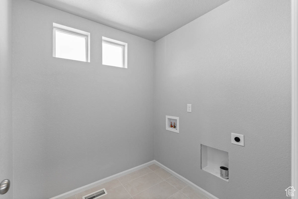 Laundry room featuring hookup for a washing machine, electric dryer hookup, and light tile patterned floors
