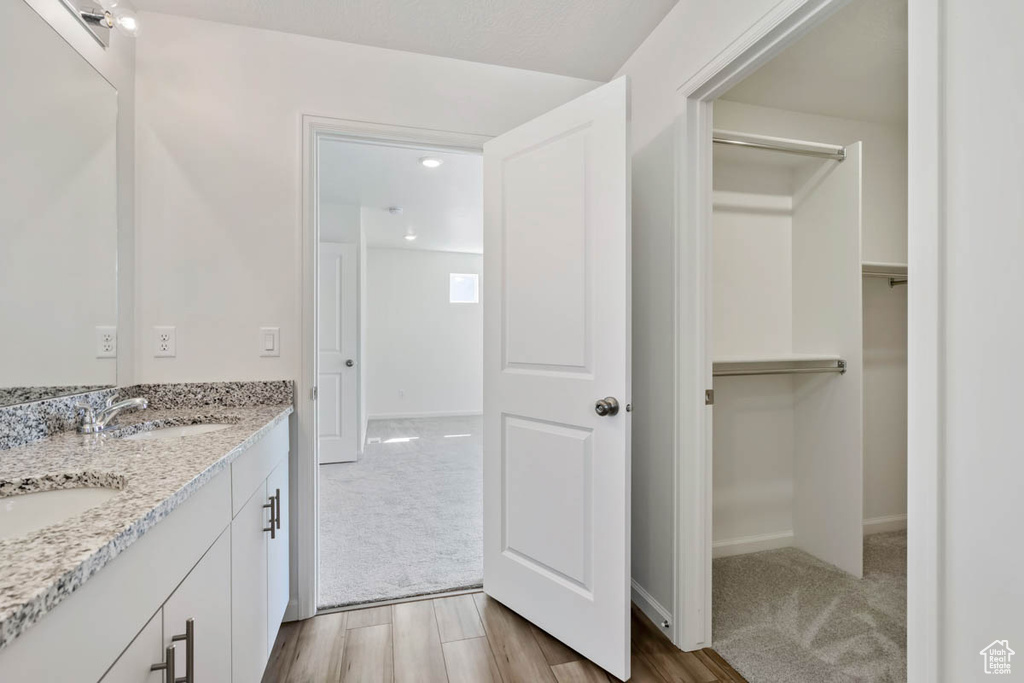 Bathroom featuring double vanity, a spacious closet, and wood finished floors