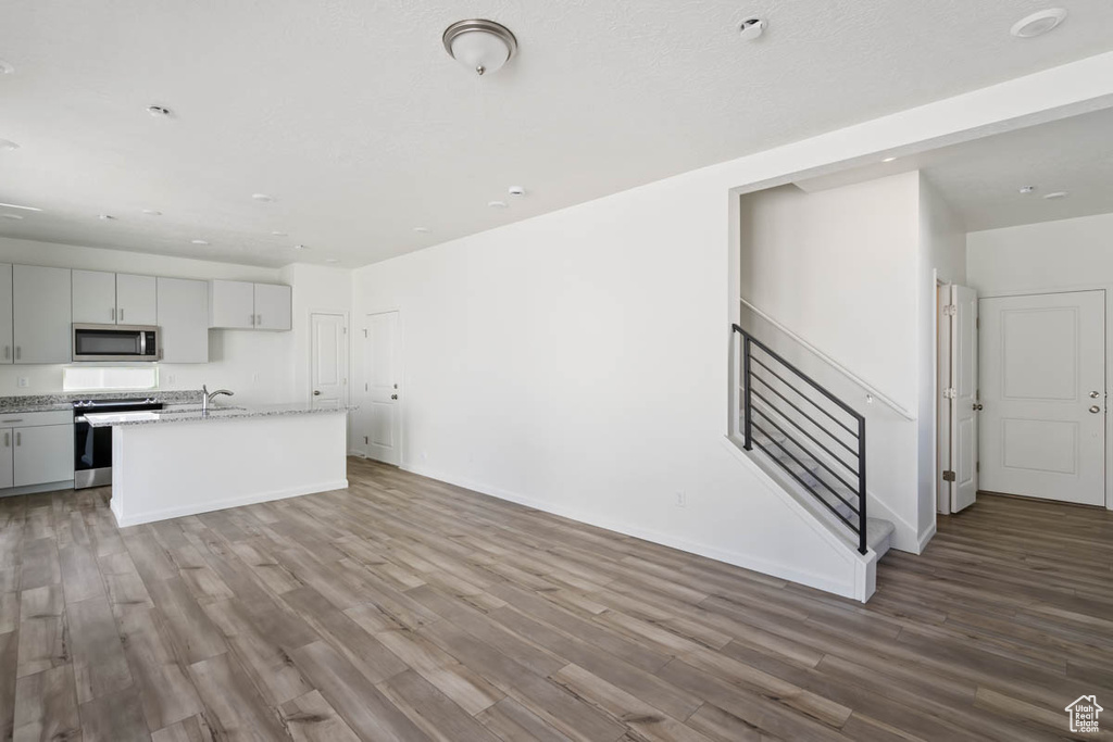 Unfurnished living room featuring wood finished floors and a sink