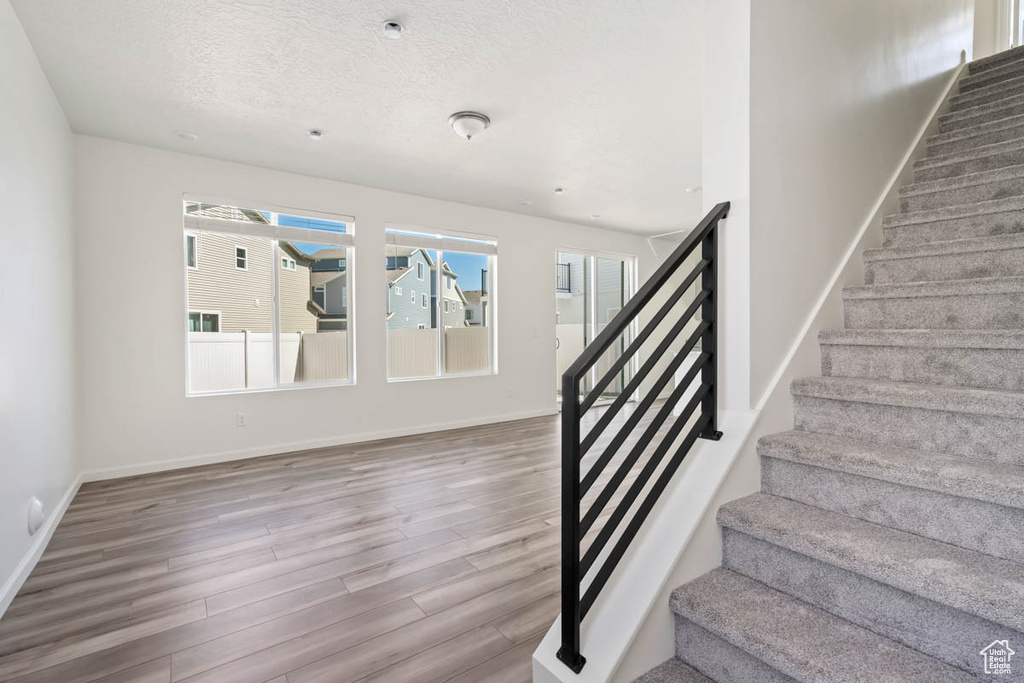 Stairs featuring wood finished floors, healthy amount of natural light, and a textured ceiling