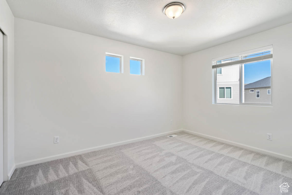 Carpeted spare room featuring baseboards